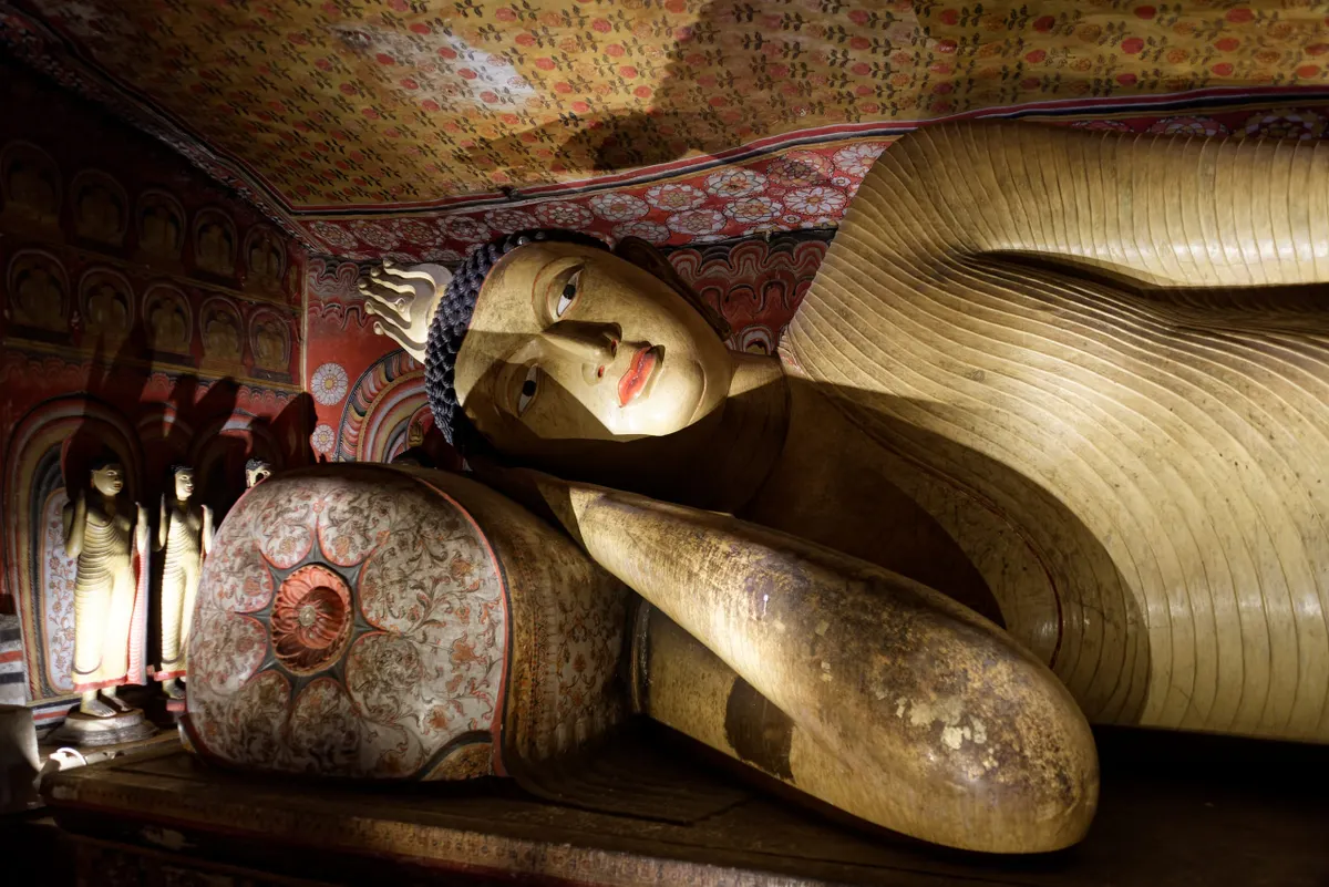 Rows of Buddha statues beneath painted ceilings inside the Dambulla cave temple