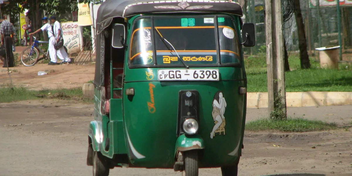 A green three-wheeler tuk-tuk on a Sri Lankan street