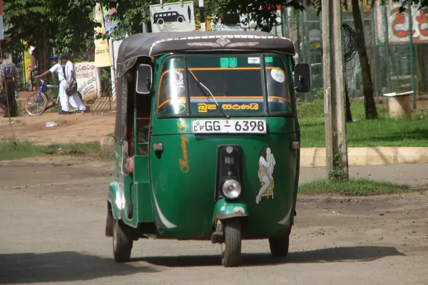 A green three-wheeler tuk-tuk on a Sri Lankan street